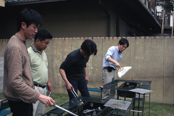 只今準備中-：
男性陣編-炭火をおこすのは男性陣の仕事。うまく火を起こすには団扇の扇ぎ方にコツがあるんですね。これ、吉田助教授が異様に上手いです。